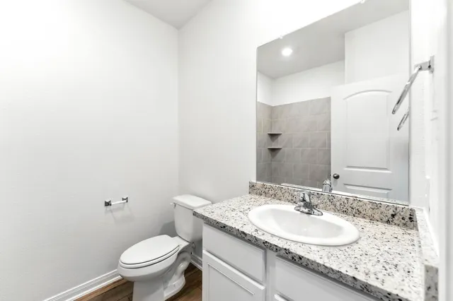 a bathroom with a granite countertop sink a toilet and a mirror