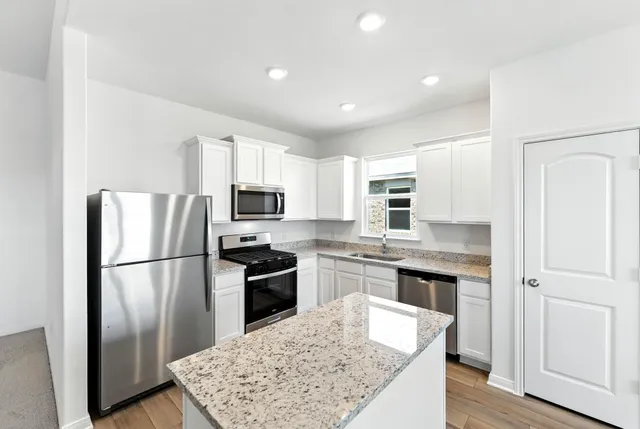 a kitchen with stainless steel appliances granite countertop a refrigerator stove microwave and sink