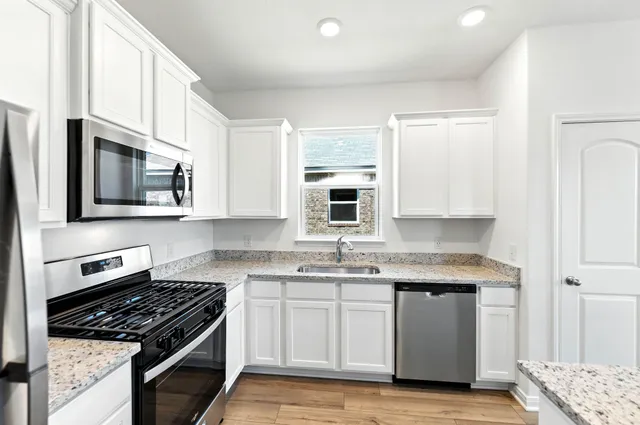 a kitchen with stainless steel appliances granite countertop a stove a sink and a microwave