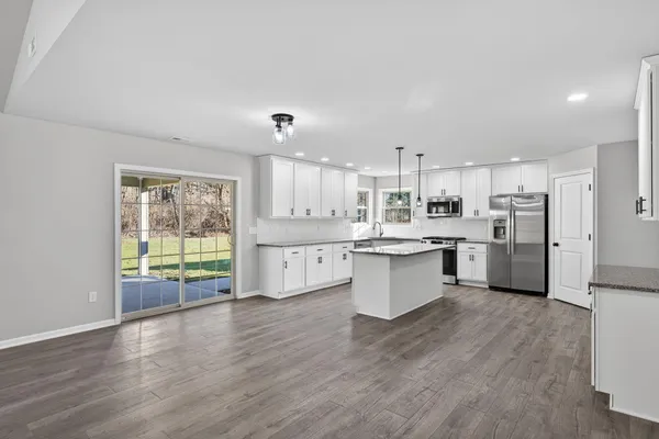 a large kitchen with a large counter top a sink stainless steel appliances and cabinets