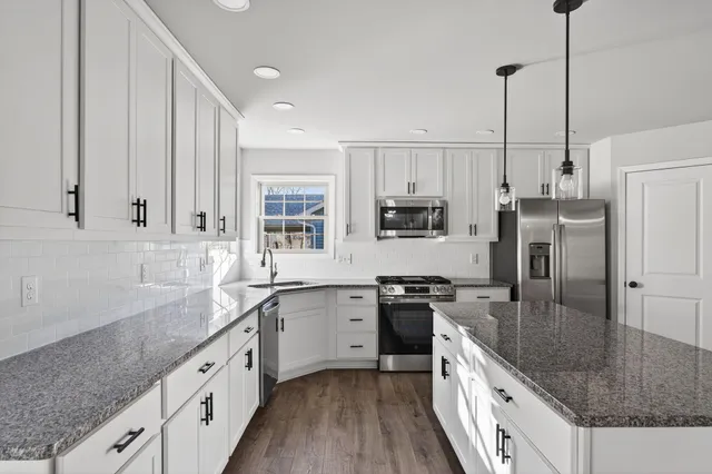 a kitchen with stainless steel appliances granite countertop a sink a stove and refrigerator