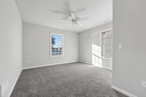 an empty room with windows and fan