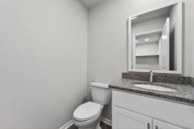 a bathroom with a granite countertop toilet and a sink