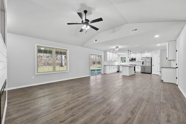 a view of an empty room with a window and wooden floor