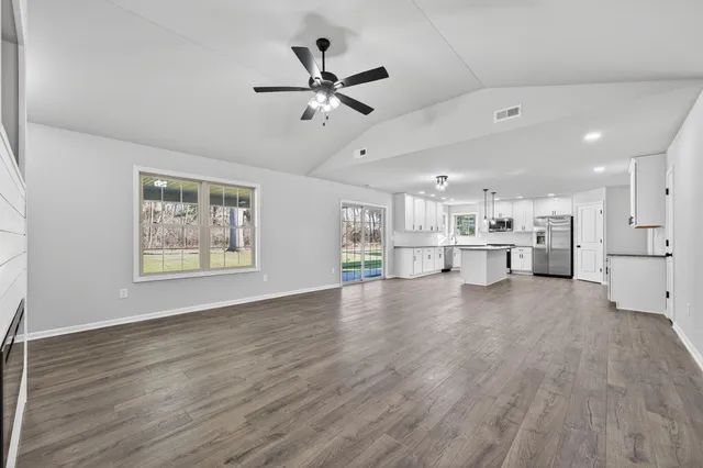 a view of an empty room with a window and wooden floor