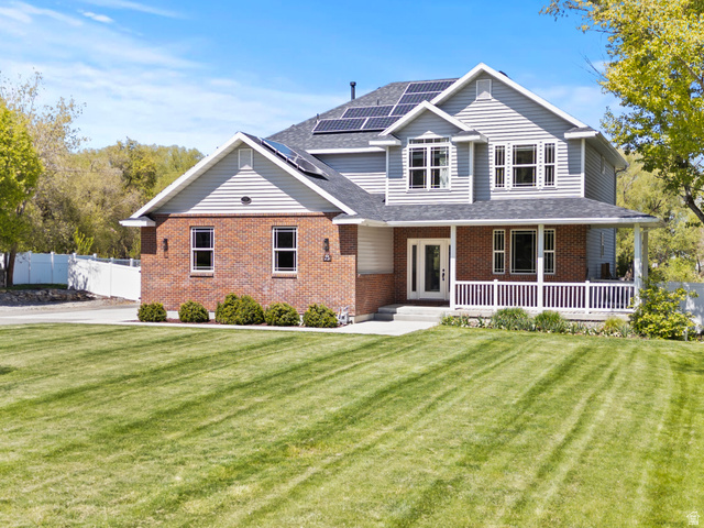 75 East 200 North Mendon, UT 84325 - Photo 4 of 36 View of front of house featuring roof mounted solar panels, a porch, brick siding, and a shingled roof