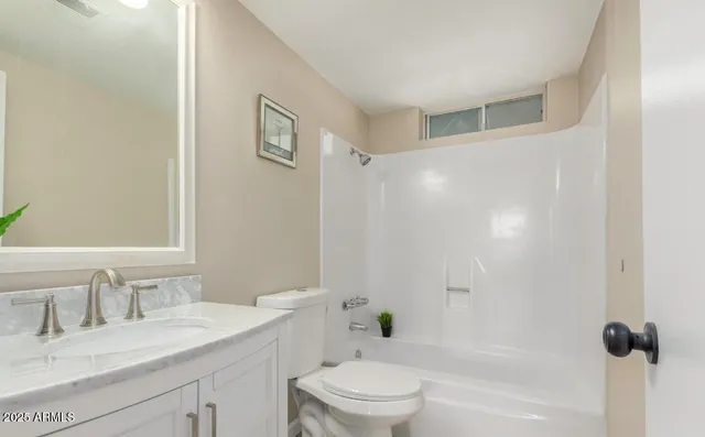 a bathroom with a granite countertop sink a toilet and shower