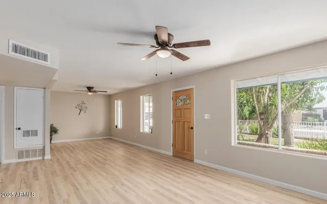a view of empty room with wooden floor and fan