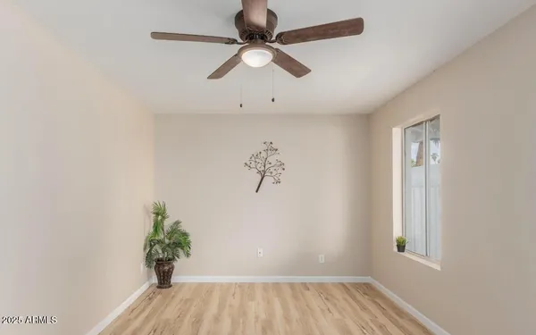 an empty room with wooden floor chandelier fan and windows