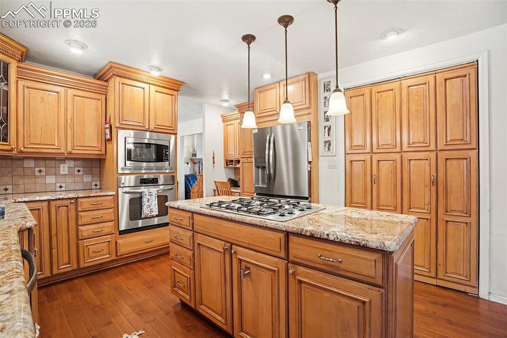 8265 Tannenbaum Road Colorado Springs, CO 80908 - Photo 11 of 50 a kitchen with stainless steel appliances granite countertop a refrigerator a stove and white cabinets with wooden floor