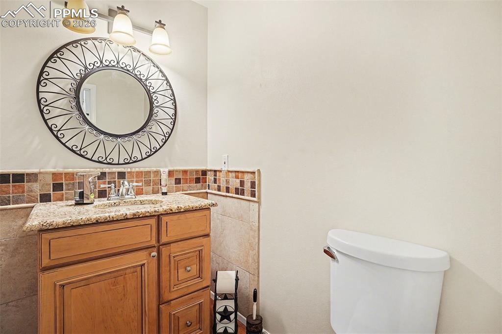 8265 Tannenbaum Road Colorado Springs, CO 80908 - Photo 18 of 50 a bathroom with a granite countertop toilet a sink and a mirror