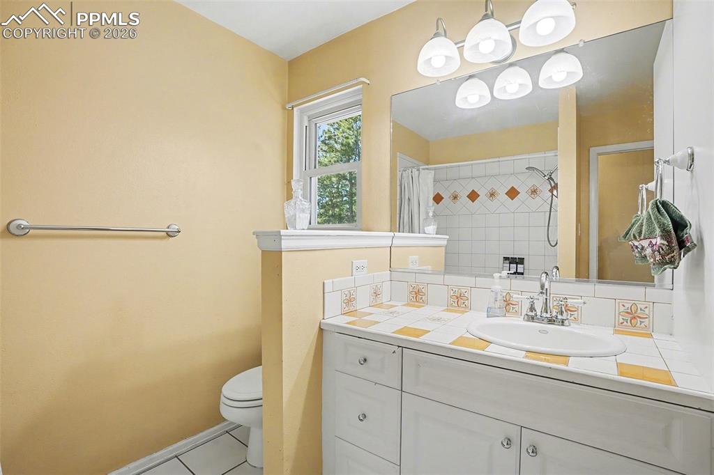 8265 Tannenbaum Road Colorado Springs, CO 80908 - Photo 25 of 50 a bathroom with a sink a toilet and a mirror