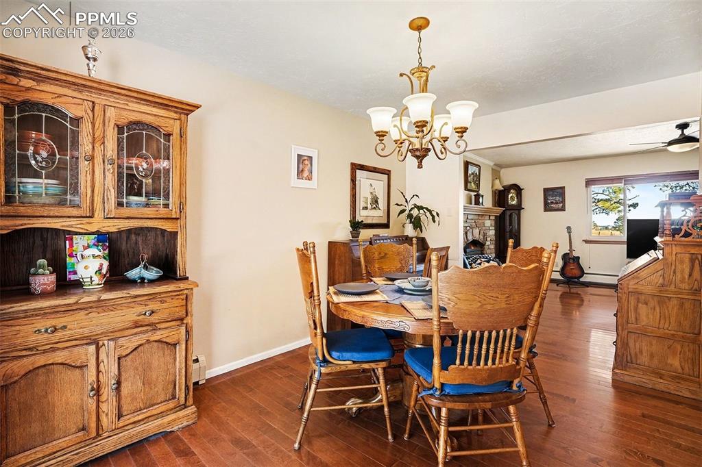 8265 Tannenbaum Road Colorado Springs, CO 80908 - Photo 9 of 50 a dining room with wooden floor a chandelier a wooden table and chairs