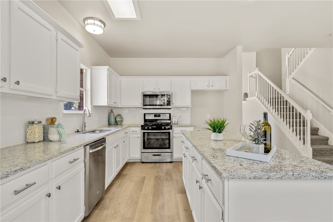 a kitchen with granite countertop a sink a stove top oven and cabinets