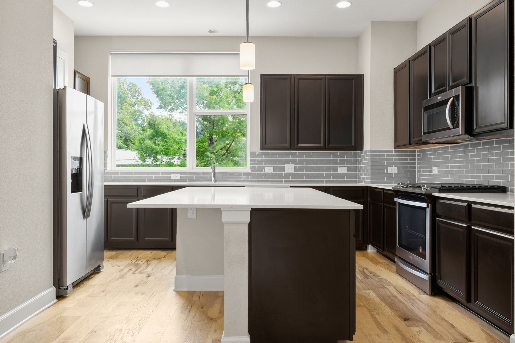 4403 Swift Path Austin, TX 78741 - Photo 4 of 32 Modern kitchen featuring rich cabinetry, a central island with a solid surface countertop, stainless steel appliances, and wood-finish flooring