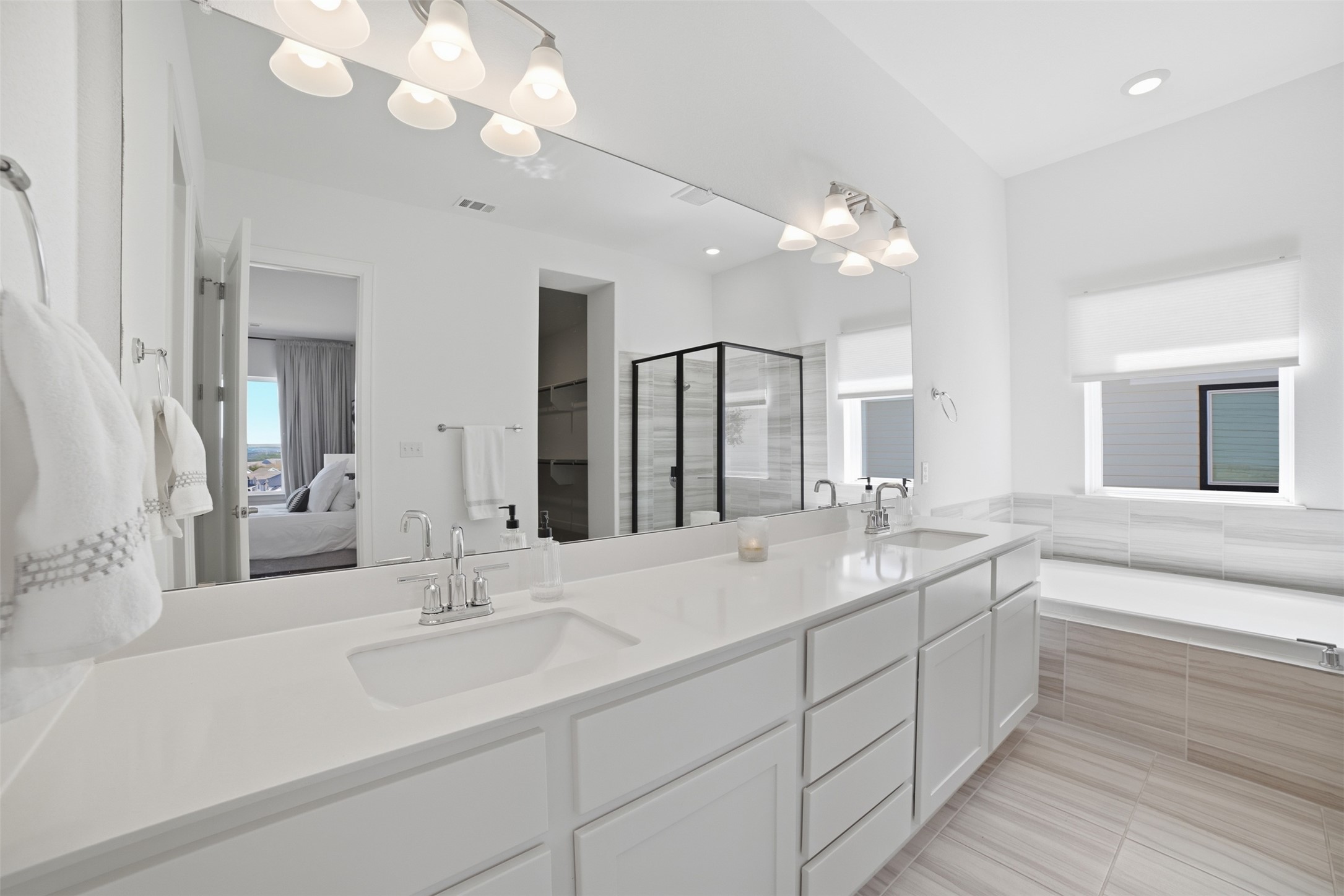 256 Smoke Tree Circle Dripping Springs, TX 78620 - Photo 22 of 40 a bathroom with double vanity sinks a large mirror and a bathtub