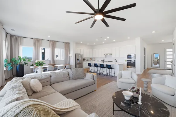 a living room with furniture kitchen view and a chandelier
