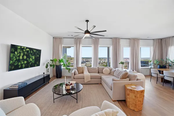 a living room with furniture ceiling fan and a large window