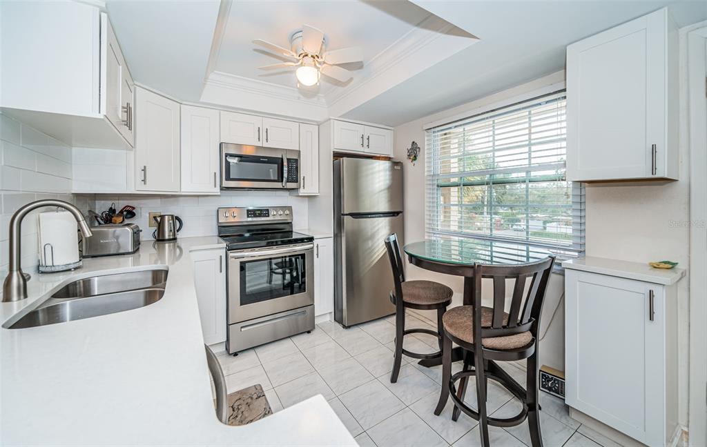 920 Virginia Street, Unit 302 Dunedin, FL 34698 - Photo 23 of 66 a kitchen with stainless steel appliances granite countertop a stove a sink dishwasher a refrigerator with a dining table and chairs