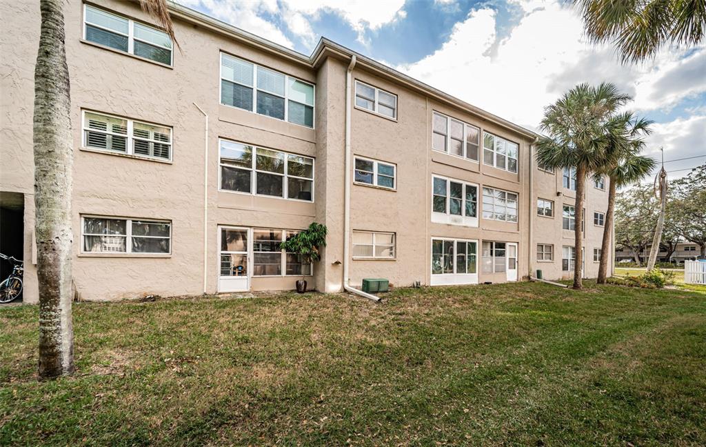 920 Virginia Street, Unit 302 Dunedin, FL 34698 - Photo 40 of 66 a large building with a big yard and potted plants in front of it