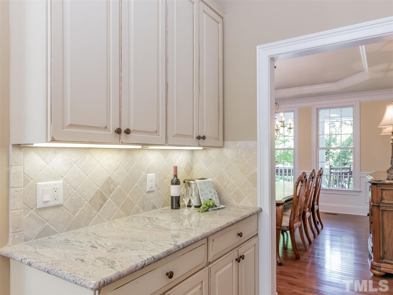 4717 Haleytree Court Raleigh, NC 27606 - Photo 14 of 30 Enjoy using the butler's pantry between the dining room and kitchen for serving! Extra cabinetry and granite counter top! Under counter lighting as well.