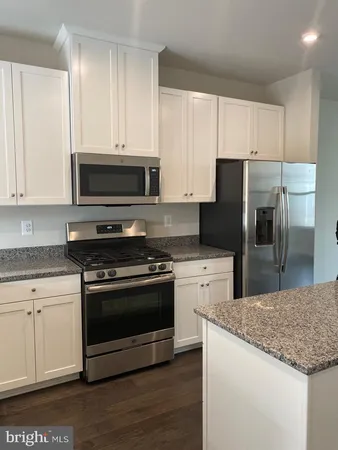 a kitchen with granite countertop a refrigerator stove and microwave