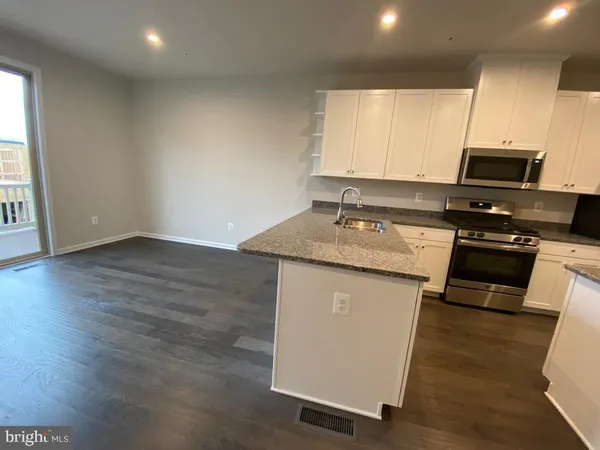 a kitchen with a sink a stove a microwave and wooden floor