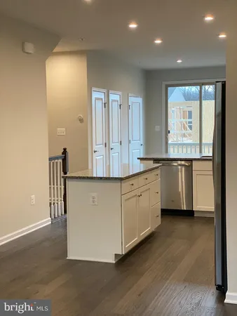 a kitchen with stainless steel appliances granite countertop a stove a sink and a refrigerator with wooden floors