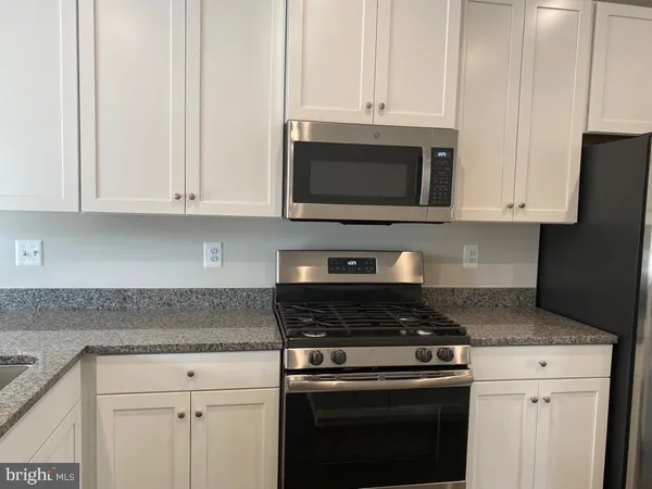 a kitchen with granite countertop white cabinets and stainless steel appliances