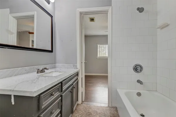 a bathroom with a granite countertop sink a mirror and a bathtub