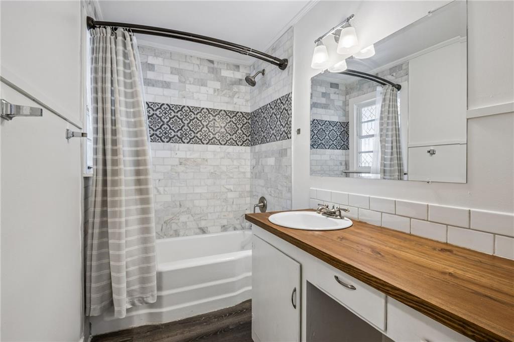 358 Peevy Street Buford, GA 30518 - Photo 13 of 18 a bathroom with a granite countertop sink a mirror a bathtub and shower