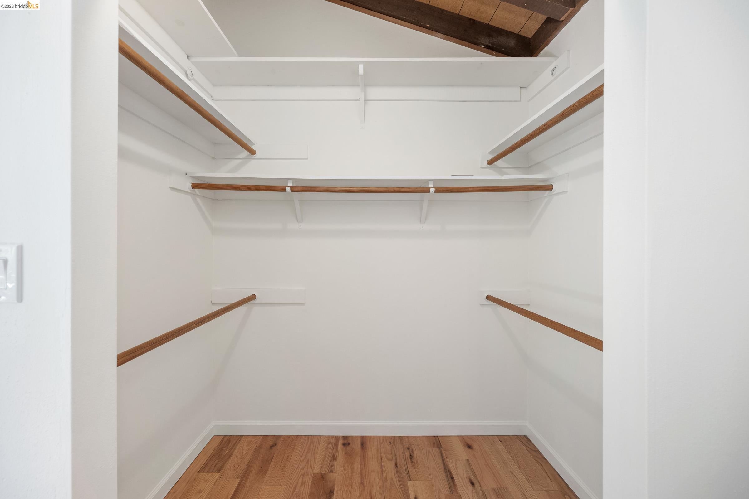 6600 Heather Ridge Way Oakland, CA 94611 - Photo 47 of 66 Walk-in closet featuring wood-finish flooring, white walls, multiple built-in shelves, and wood hanging rods