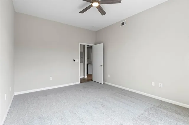 an empty room with a ceiling fan and carpet