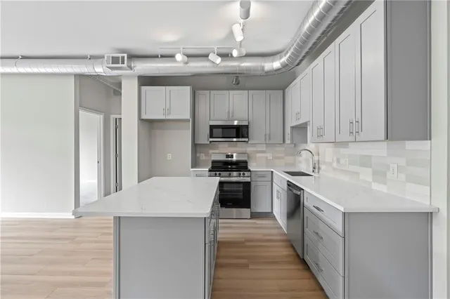 a kitchen with kitchen island granite countertop a sink stainless steel appliances and cabinets
