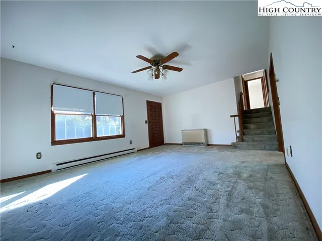 an empty room with windows and ceiling fan