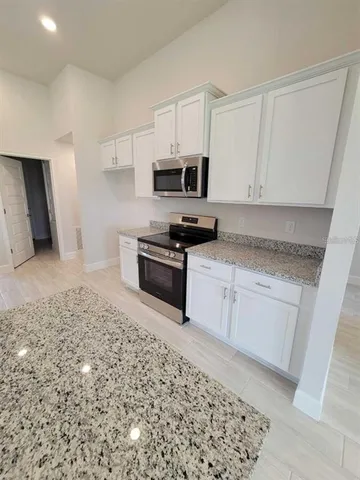 a kitchen with granite countertop white cabinets and stainless steel appliances