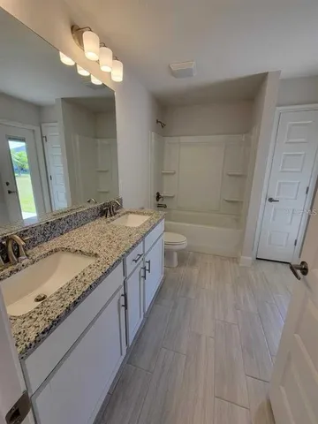a bathroom with a granite countertop double vanity sink and a mirror