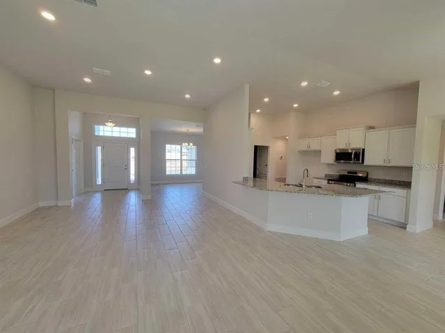 a view of kitchen with kitchen island granite countertop stainless steel appliances refrigerator sink and cabinets