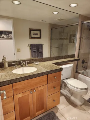 a bathroom with a granite countertop sink mirror vanity and toilet