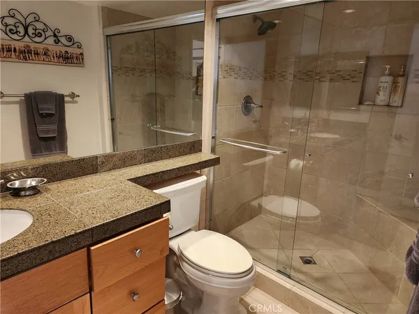 a bathroom with a granite countertop sink toilet and shower