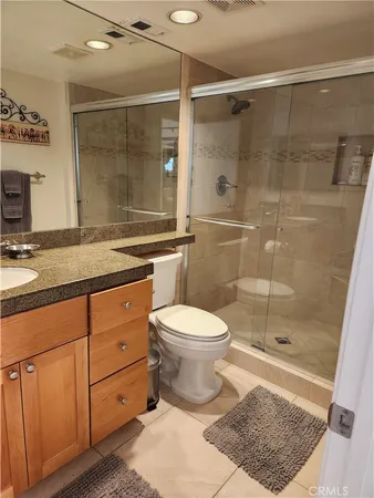 a bathroom with a granite countertop sink toilet a mirror and shower