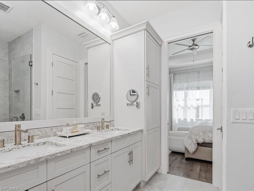 6827 Saona Court Naples, FL 34113 - Photo 11 of 36 a en suite bathroom with a granite countertop sink mirror and a bath tub