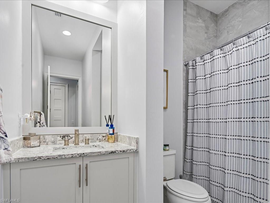 6827 Saona Court Naples, FL 34113 - Photo 13 of 36 a bathroom with a granite countertop sink toilet and shower