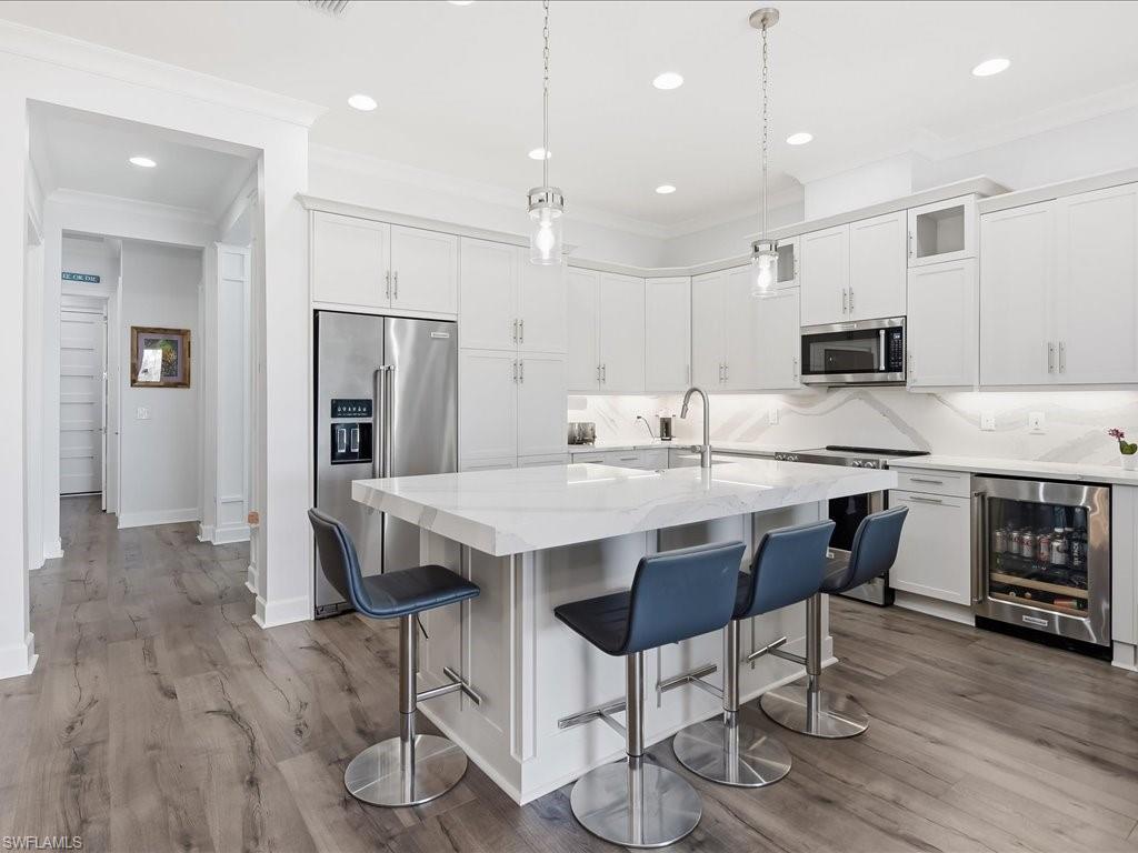 6827 Saona Court Naples, FL 34113 - Photo 19 of 36 a kitchen with kitchen island granite countertop a center island a refrigerator and a stove top oven