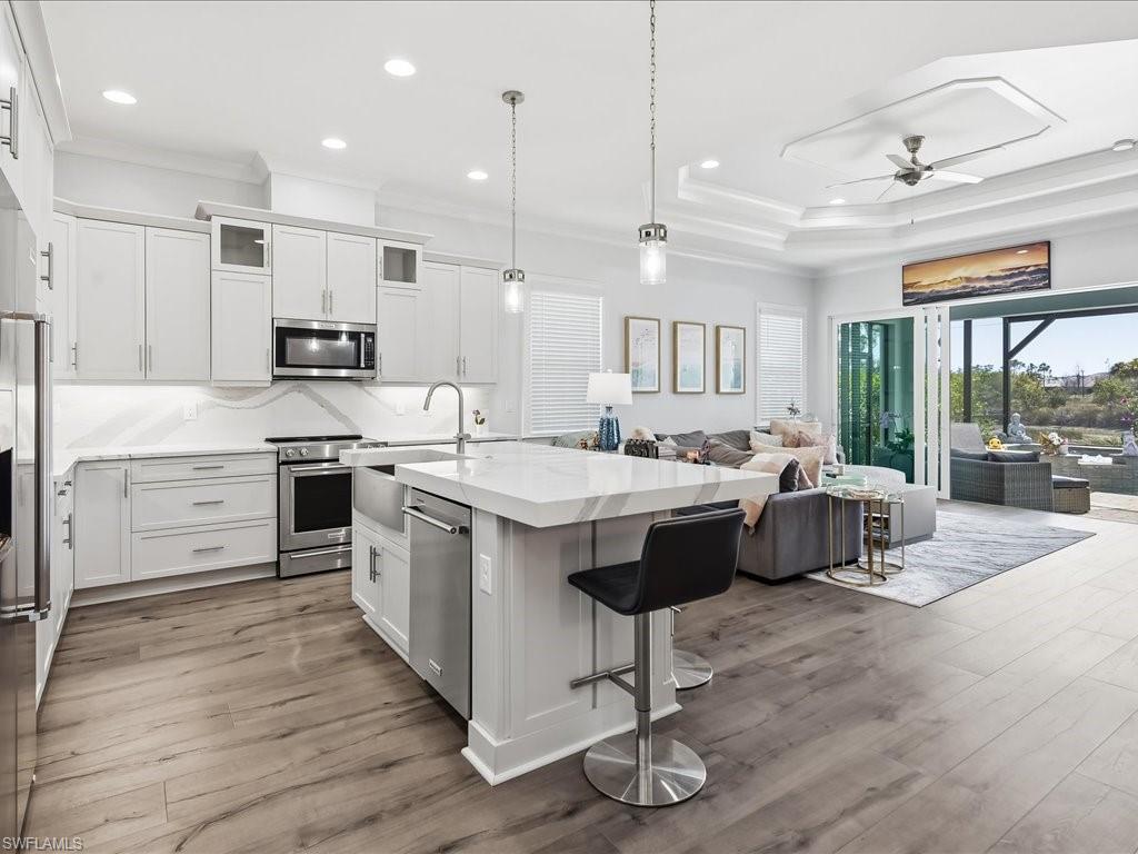 6827 Saona Court Naples, FL 34113 - Photo 2 of 36 a large kitchen with kitchen island a large counter top a sink stainless steel appliances and cabinets