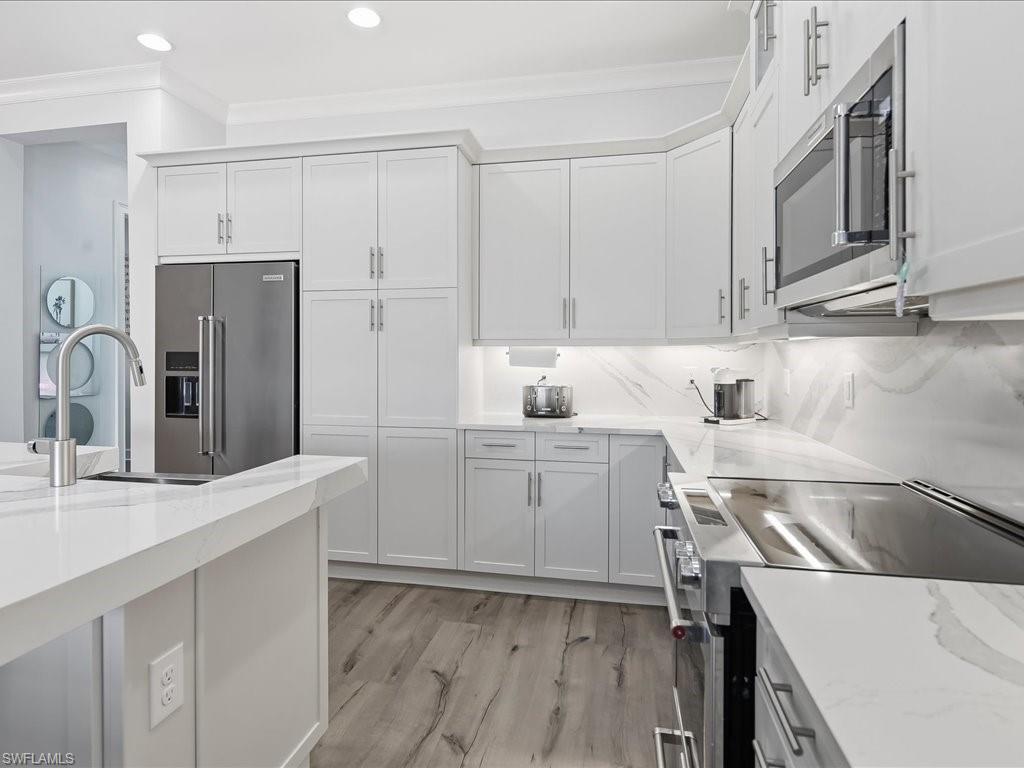 6827 Saona Court Naples, FL 34113 - Photo 3 of 36 a kitchen with a sink cabinets and stainless steel appliances