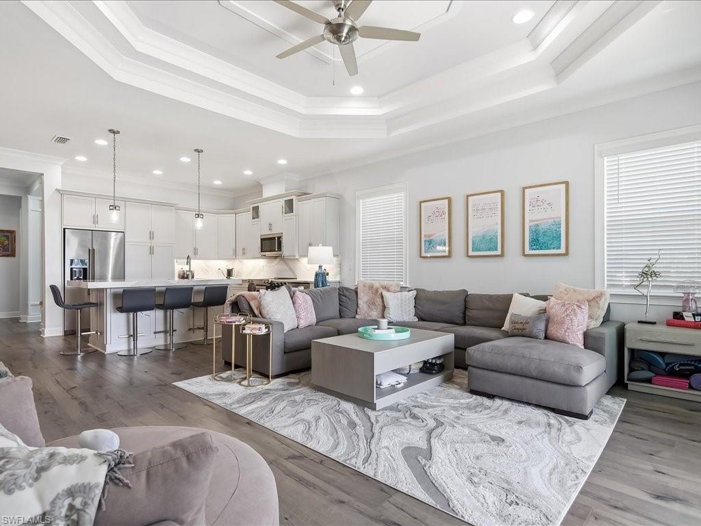 6827 Saona Court Naples, FL 34113 - Photo 4 of 36 a living room with couches and kitchen view with wooden floor