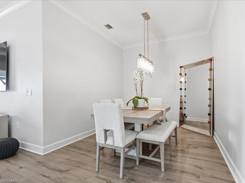 6827 Saona Court Naples, FL 34113 - Photo 9 of 36 a view of a dining room with furniture and wooden floor