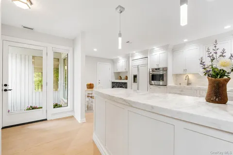a large white kitchen with a refrigerator a stove top oven a sink and cabinets