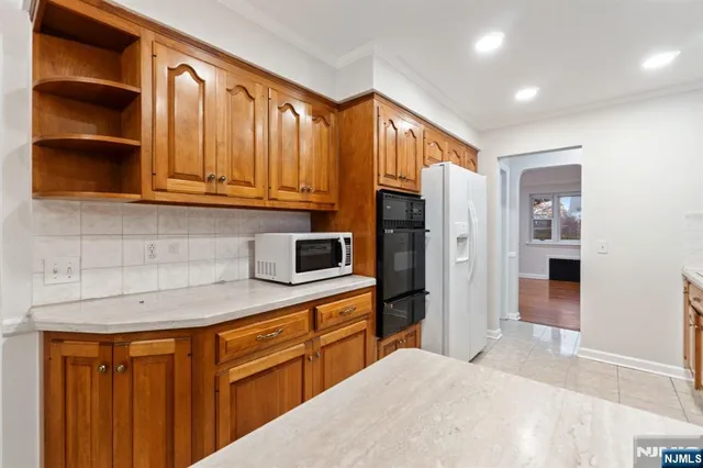 a kitchen with stainless steel appliances granite countertop a refrigerator a sink dishwasher and wooden cabinets with wooden floor